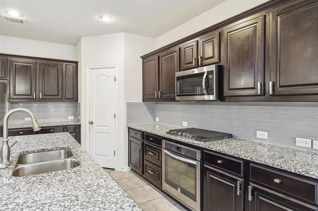 a kitchen with stainless steel appliances granite countertop a sink stove and microwave