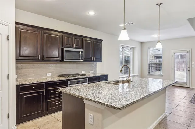a kitchen with stainless steel appliances granite countertop a sink a stove and a refrigerator