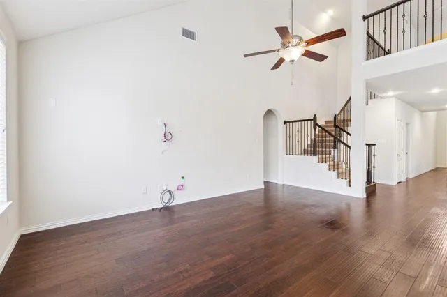 a view of empty room with wooden floor and ceiling fan