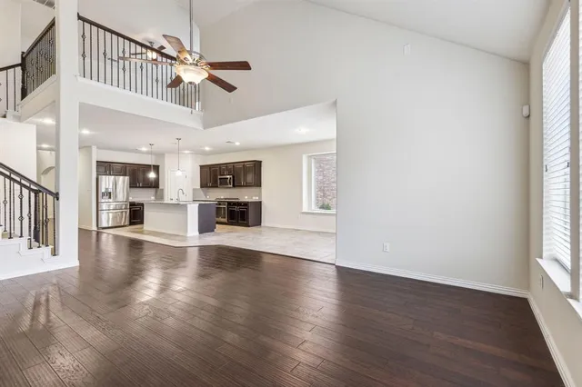 an open kitchen with wooden floor a ceiling fan and windows
