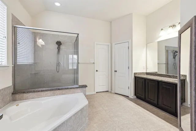 a spacious bathroom with a granite countertop tub sink shower and mirror