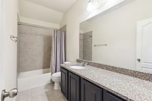 a bathroom with a granite countertop sink a toilet and shower