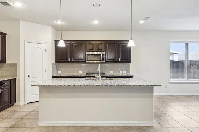 a large kitchen with granite countertop a stove a sink and a refrigerator