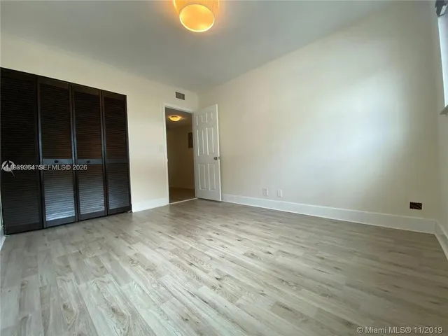 an empty room with wooden floor and closet