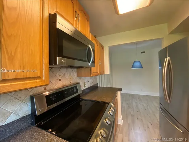 a kitchen with stainless steel appliances granite countertop a refrigerator and a stove top oven