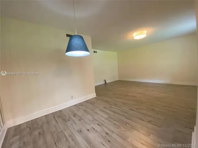 an empty room with wooden floor and exposed radiator