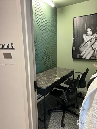 a view of a workspace with furniture and a window