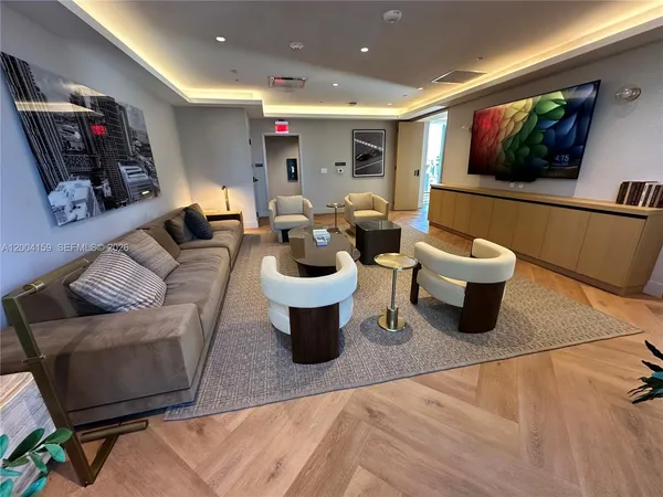 a living room with stainless steel appliances furniture a rug and kitchen view