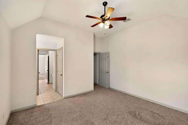 an empty room with a chandelier fan and windows