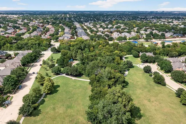 an aerial view of a residential houses with outdoor space and trees