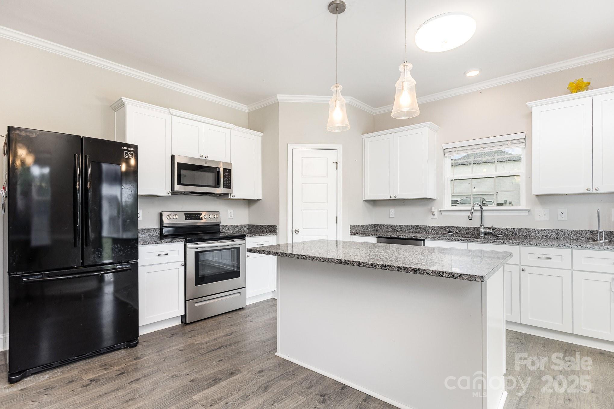 4026 Pigg Mattox Road Monroe, NC 28112 - Photo 7 of 31 a kitchen with a center island wooden floor and stainless steel appliances