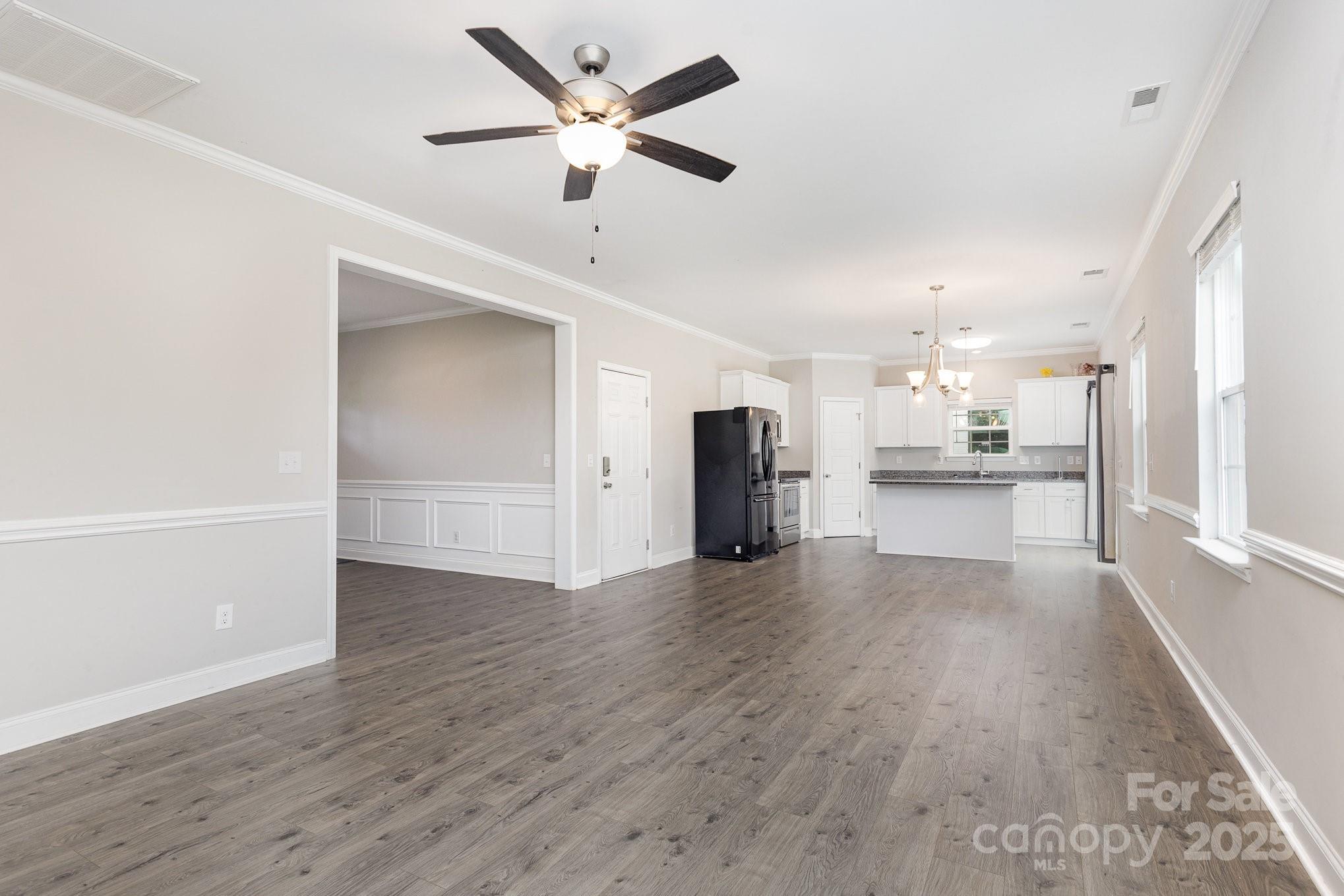 4026 Pigg Mattox Road Monroe, NC 28112 - Photo 10 of 31 an empty room with wooden floor and a kitchen view