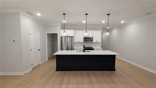 a kitchen with kitchen island a sink stainless steel appliances and a counter top space