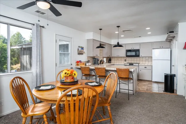 a dining room with stainless steel appliances granite countertop a dining table chairs and a refrigerator