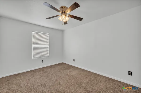 an empty room with a window and a fan
