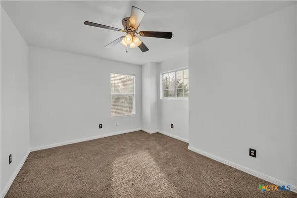 a view of an empty room with chandelier fan