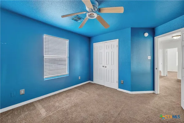 an empty room with windows and fan