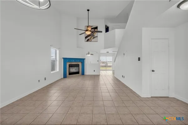a view of a livingroom with a fireplace a ceiling fan and entryway
