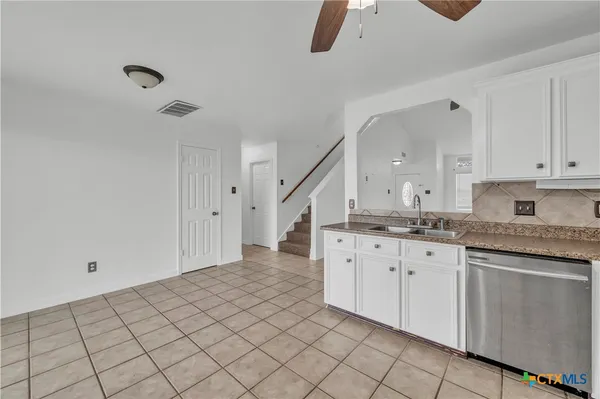 a kitchen with granite countertop a sink a stove top oven and cabinetry