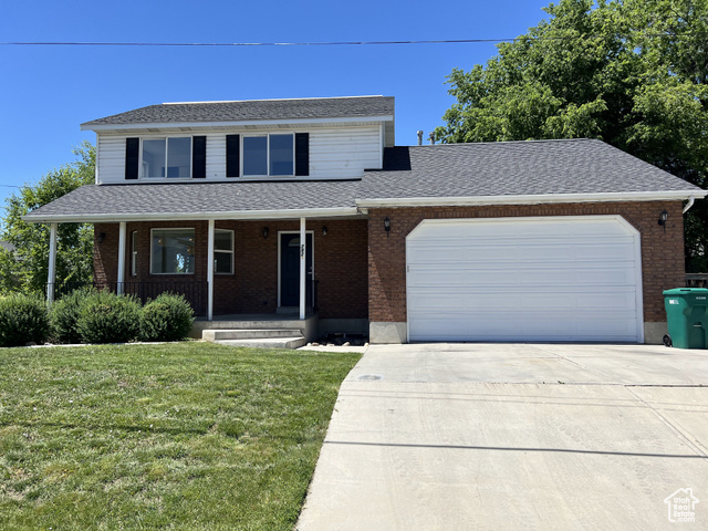 792 South Main Street Orem, UT 84058 - Photo 1 of 1 Traditional home featuring a front lawn, driveway, an attached garage, brick siding, and covered porch