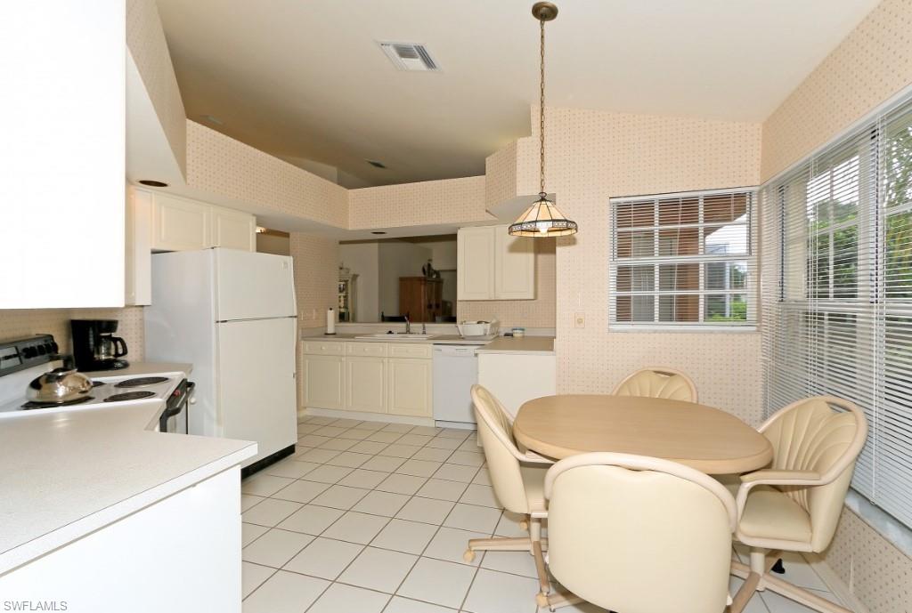 214 Napa Ridge Road East Naples, FL 34119 - Photo 5 of 12 a kitchen with a refrigerator a sink dishwasher a dining table and chairs with wooden floor