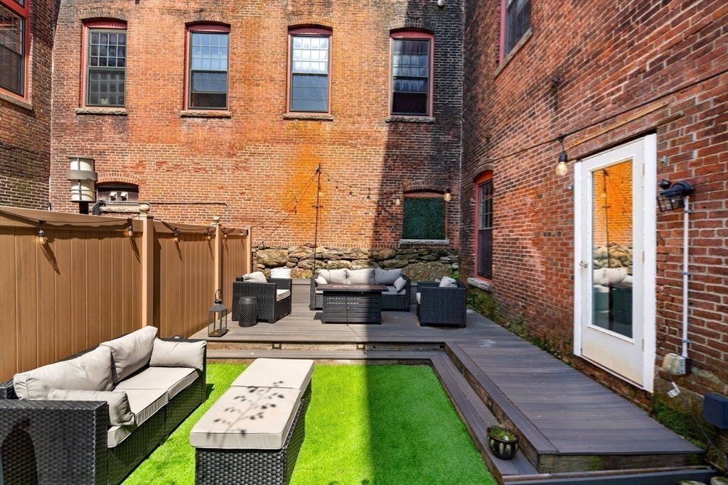 1511 Main Street, Unit B101 Worcester, MA 01603 - Photo 28 of 41 a view of a patio with couches chairs potted plants and wooden floor