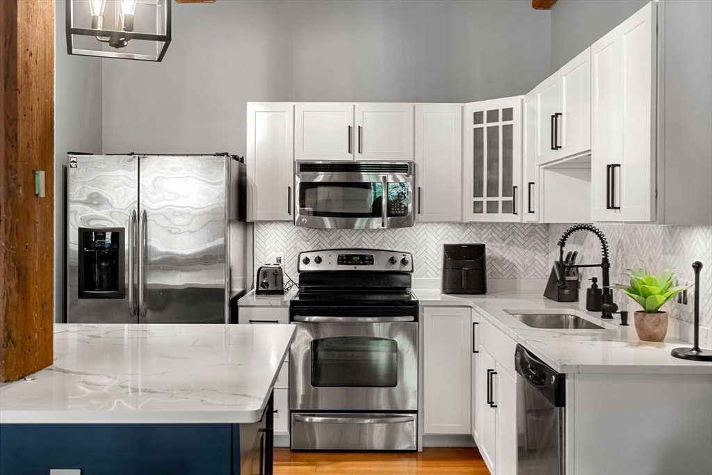 1511 Main Street, Unit B101 Worcester, MA 01603 - Photo 3 of 41 a kitchen with kitchen island granite countertop a stove a sink and a refrigerator
