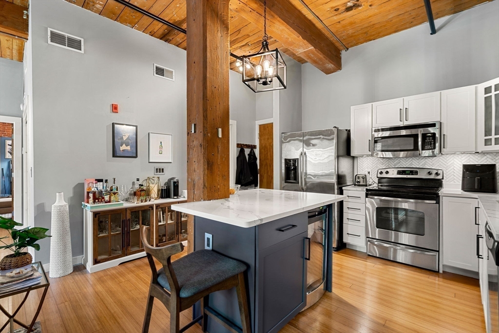 1511 Main Street, Unit B101 Worcester, MA 01603 - Photo 4 of 41 a kitchen with stainless steel appliances a stove a sink dishwasher and a refrigerator with wooden floor