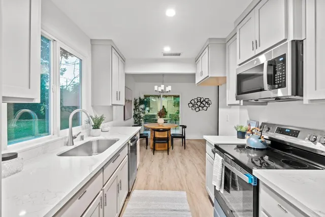 a kitchen with stainless steel appliances granite countertop a sink dishwasher stove and microwave with wooden floor