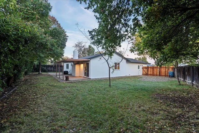 a view of a house with backyard and a tree