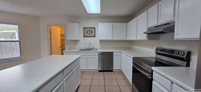a kitchen with a sink stove top oven and cabinets