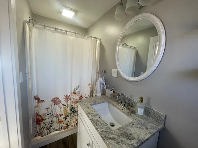 a bathroom with a granite countertop sink a mirror and a shower