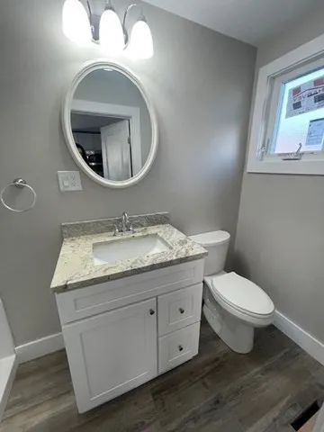 a bathroom with a granite countertop toilet a sink and a mirror