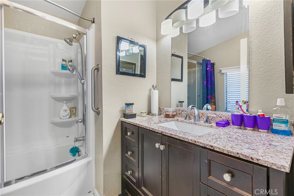 21650 Temescal Canyon Road, Unit 13 Corona, CA 92883 - Photo 13 of 21 a bathroom with a granite countertop tub a sink and a mirror