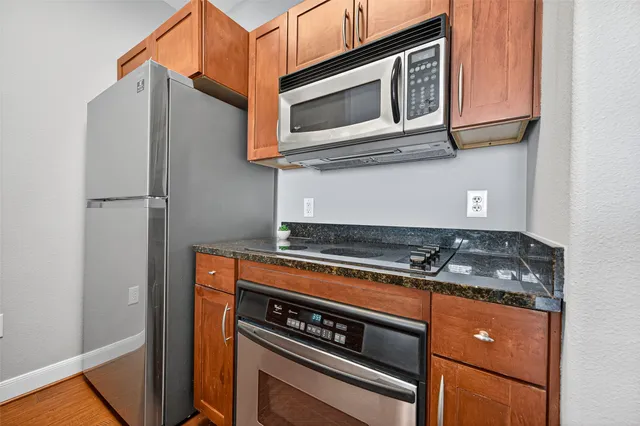 a kitchen with stainless steel appliances granite countertop a refrigerator a stove and a wooden floors