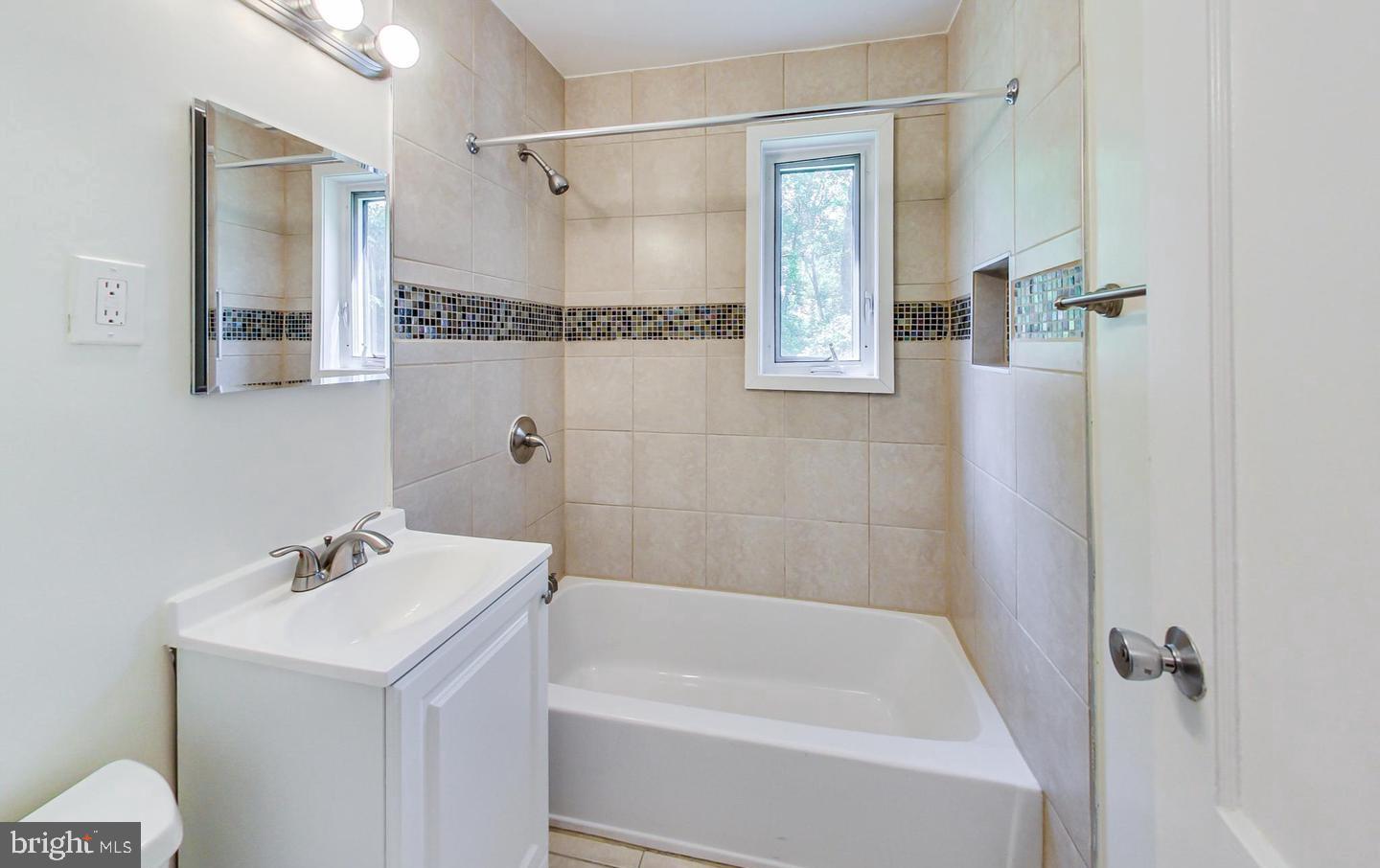 10301 Montrose Avenue, Unit 101 Bethesda, MD 20814 - Photo 11 of 27 a bathroom with a bathtub a shower a sink and a mirror