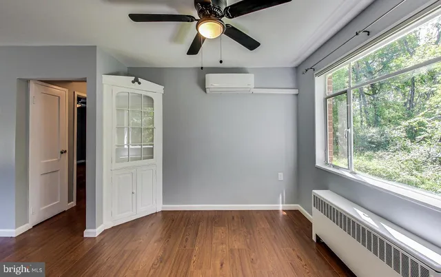 an empty room with wooden floor fan and windows