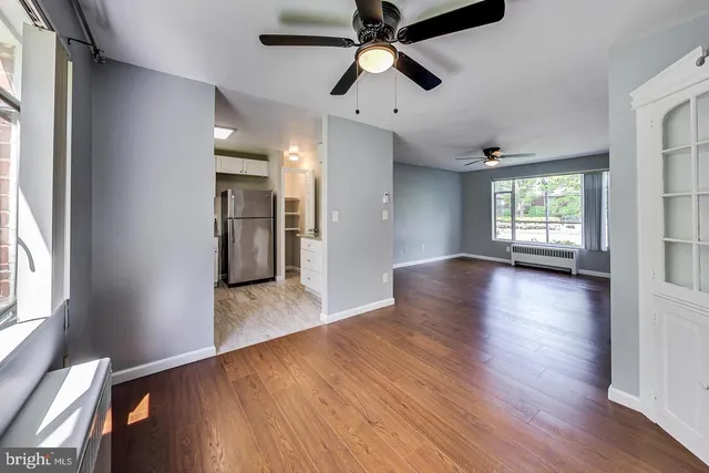 a view of an empty room with wooden floor and a window