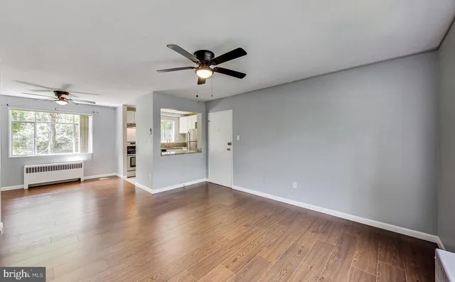 a view of an empty room with a window and wooden floor