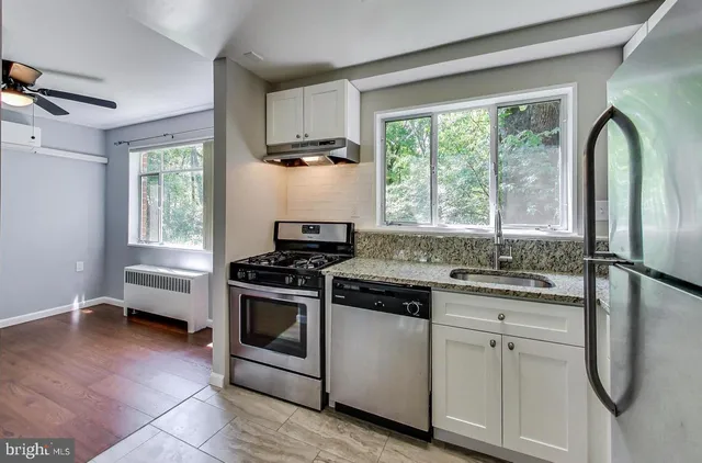 a kitchen with white cabinets appliances and window