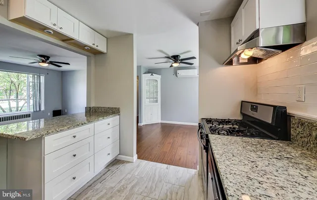 a kitchen with granite countertop a stove a sink and a wooden floor