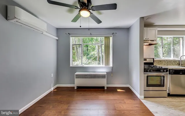 a view of an empty room with a window and wooden floor