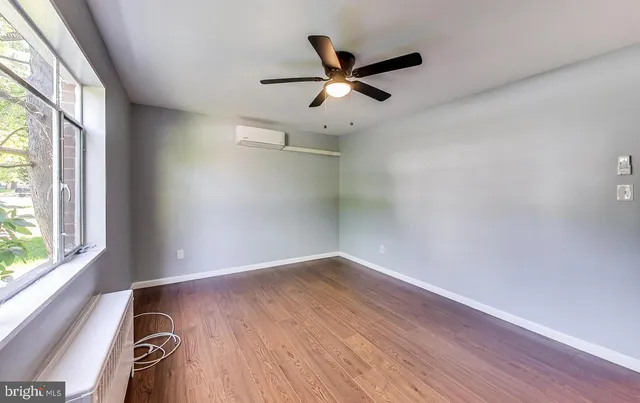 an empty room with wooden floor fan and windows