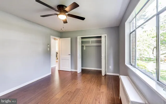 a view of an empty room with a window and wooden floor