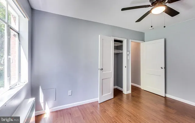an empty room with wooden floor chandelier fan and windows