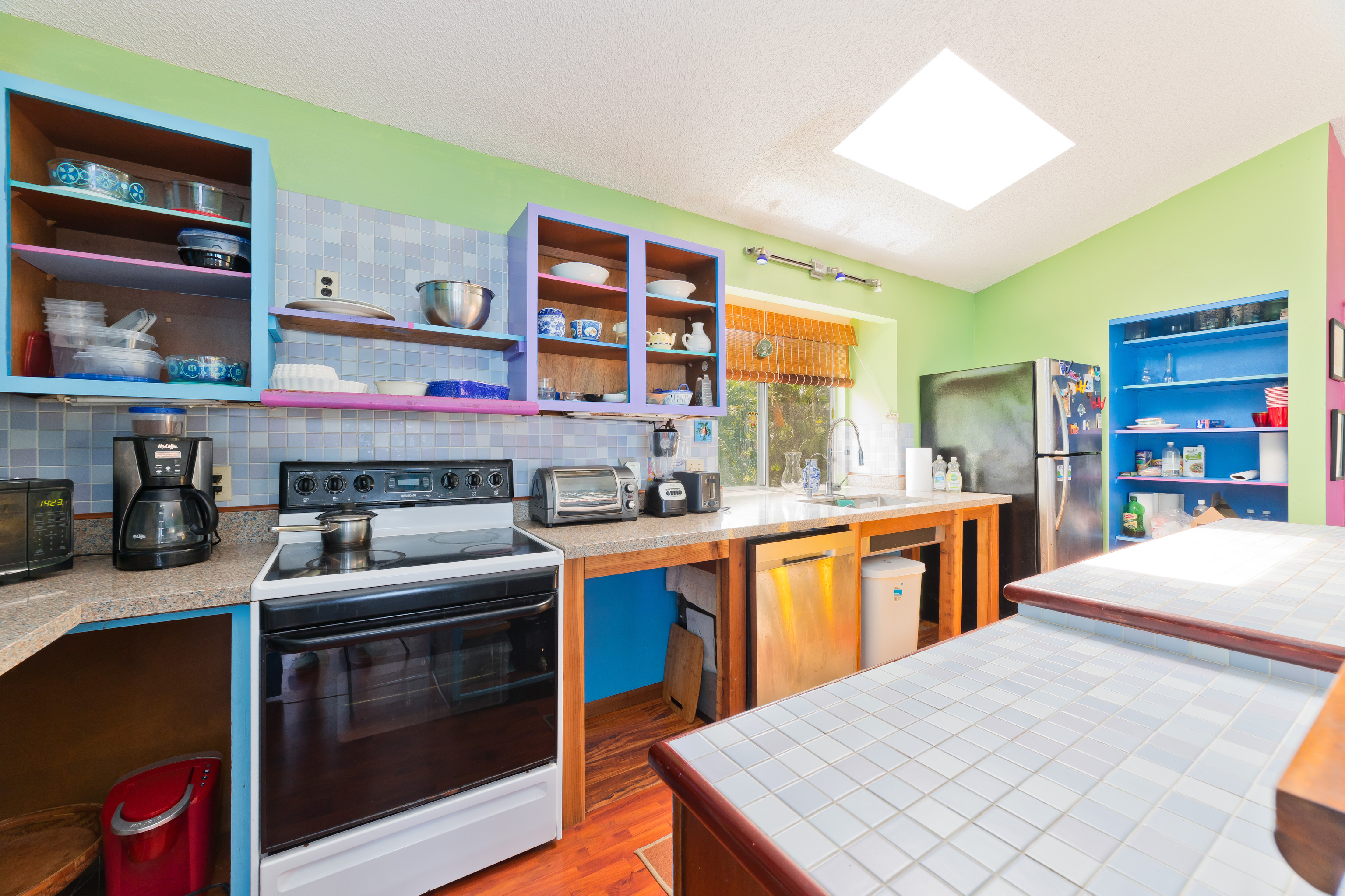 82-6301 Puuhonua Road Captain Cook, HI 96704 - Photo 12 of 27 a kitchen with stainless steel appliances granite countertop a stove a sink dishwasher and cabinets with wooden floor