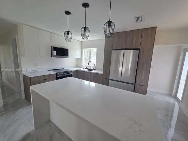 a large kitchen with stainless steel appliances a large counter top space wooden floor and window