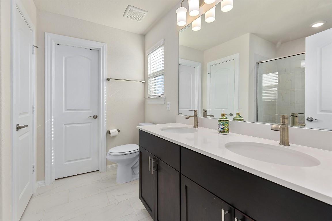 5513 Durango Pass Austin, TX 78724 - Photo 20 of 31 a bathroom with a double vanity sink toilet and a mirror