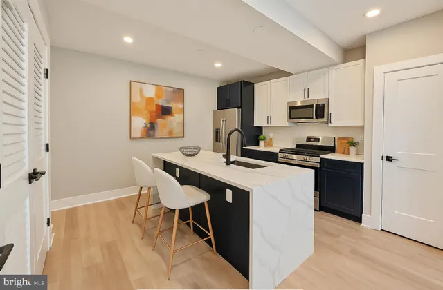 a kitchen with stainless steel appliances kitchen island granite countertop a sink cabinets and wooden floor
