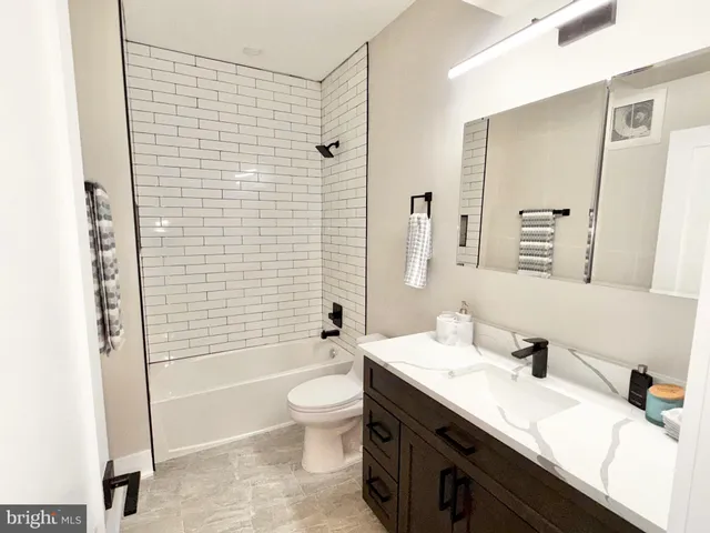 a bathroom with a bathtub shower sink vanity mirror and toilet